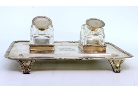 Tinteiro em prata com dois depósitos em vidro, tampas e bandeja com frisos, assente sobre quatro pés em forma de garras.