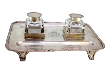 Tinteiro em prata com dois depósitos em vidro, tampas e bandeja com frisos, assente sobre quatro pés em forma de garras.