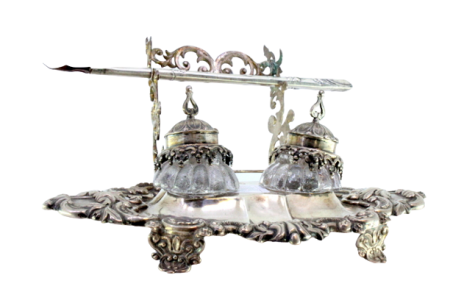 Tinteiro em prata relevada com dois depósitos em vidro, porta canetas e assente em quatro pés.