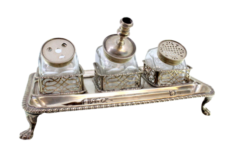 Tinteiro em prata com gradinha nos três depósitos em vidro com frisos envolventes e assente em quatro pés em forma de garras.