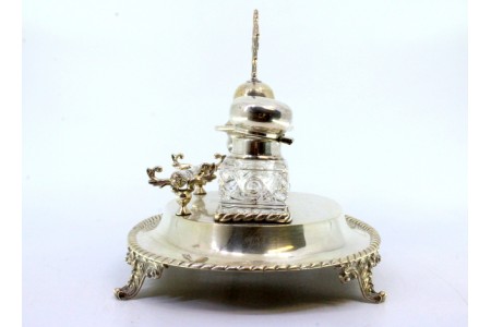 Tinteiro em prata com dois depósitos em vidro assente em base frisada com campainha, suporte para canetas e com quatro pés relevados.