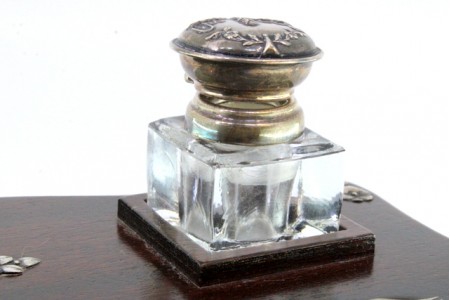 Tinteiro em madeira envernizada com motivos florais aplicados em prata no depósito e na caneta.