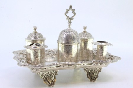 Tinteiro em prata cinzelada dois porta penas, dois depósitos, campainha e assente sobre quatro pés com relevos florais.