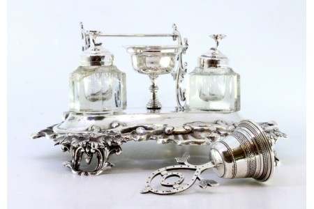 Tinteiro em prata com dois depósitos em vidro facetado,  pomo nas tampas,  campainha,  porta penas, com relevos e base recortada com quatro pés