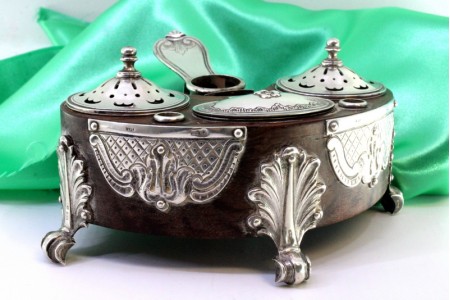 Tinteiro em em pau santo com aplicações em prata no tinteiro, areeiro, suportes para penas e assente em três pés em forma de palmas.