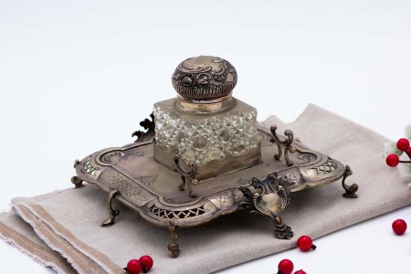  Tinteiro em prata recortada, motivos florais gravados com depósito de vidro e porta penas, assente em oito pés com cartelas para monogramas.