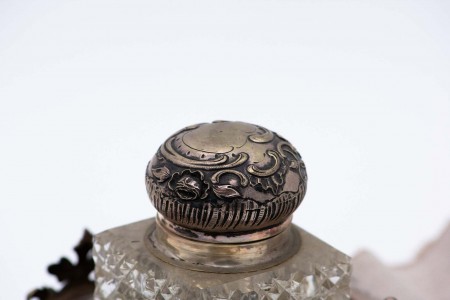  Tinteiro em prata recortada, motivos florais gravados com depósito de vidro e porta penas, assente em oito pés com cartelas para monogramas.