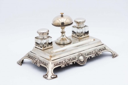 Tinteiro de prata relevada, cartela para monograma com dois depósitos em vidro  assente em quatro pés recortados.