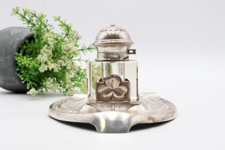 Tinteiro com estrutura em prata relevada em forma de ferradura e um depósito em vidro com tampa em alto relevo