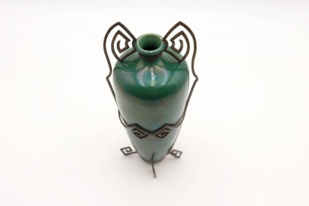 Jarra de cerâmica verde em forma de ânfora e estrutura em prata com enrolamentos.