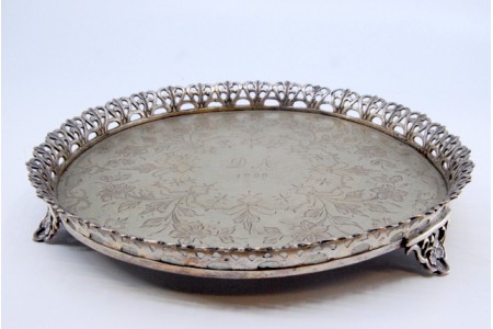 Bilheteira em prata com gradinha e centro gravado com motivos florais, assente em três pés.