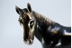 Cavalo em prata nielada em posição de trote.
