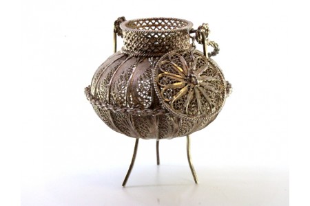 Pote em prata de filigrana com relevos e aplicações assente em três pés.