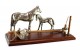 Conjunto de cavalo e potro com sela e balde com esfregona em prata assente em base de madeira envernizada.