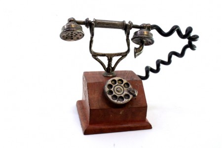 Miniatura de telefone antigo em prata com base em madeira.