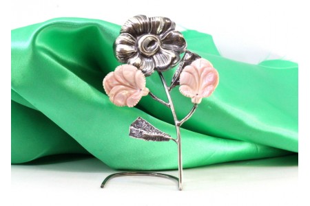Flor em prata com relevos e aplicações de cerâmica em forma de folhas.