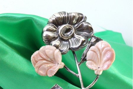 Flor em prata com relevos e aplicações de cerâmica em forma de folhas.