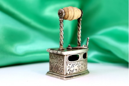 Ferro de engomar em prata com aplicações e relevos, pega em madeira e descanso 