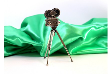 Câmara de filmar antiga em prata com tripé articulado.