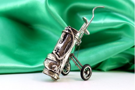 Carrinho de golfe em prata em vulto perfeito com três tacos.